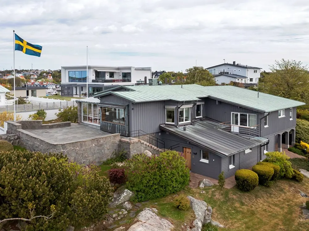 Exteriörbild av en villa i Långedrag med terrasserad tomt, naturstensmurar och utsikt över skärgården.