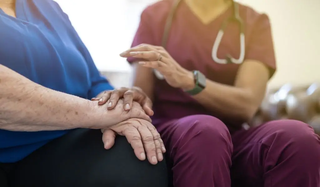 En läkare håller en patients hand under ett vårdbesök - offentlig sjukvård i Spanien