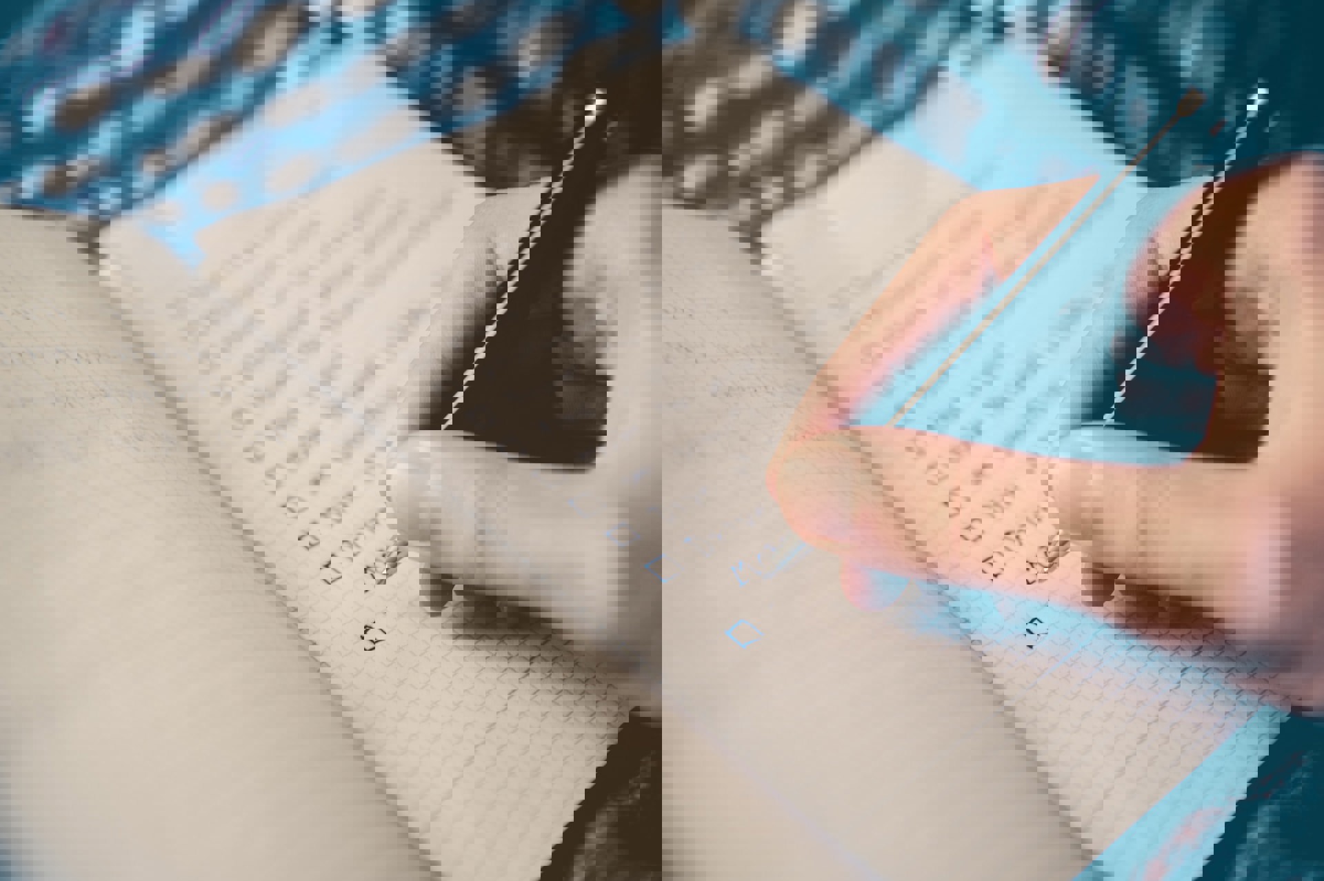 människa som håller i en penna och skriver i ett anteckningsblock