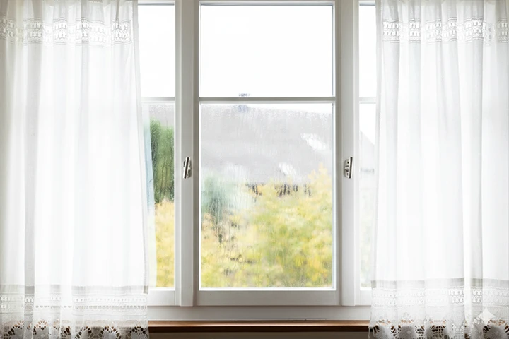 Fönster med gardiner med kondens
