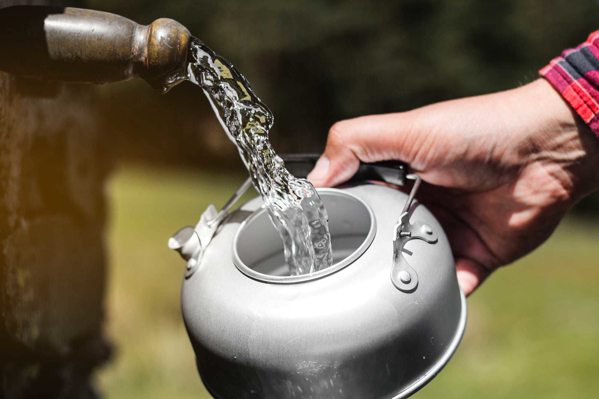 person som tar vatten från en pump