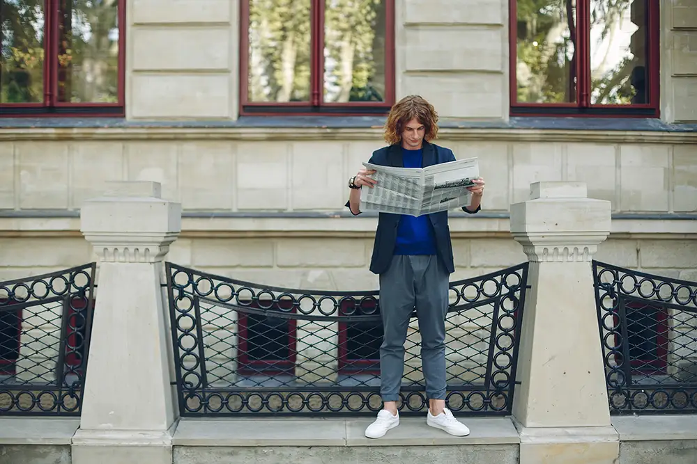 man som står med en tidning och läser