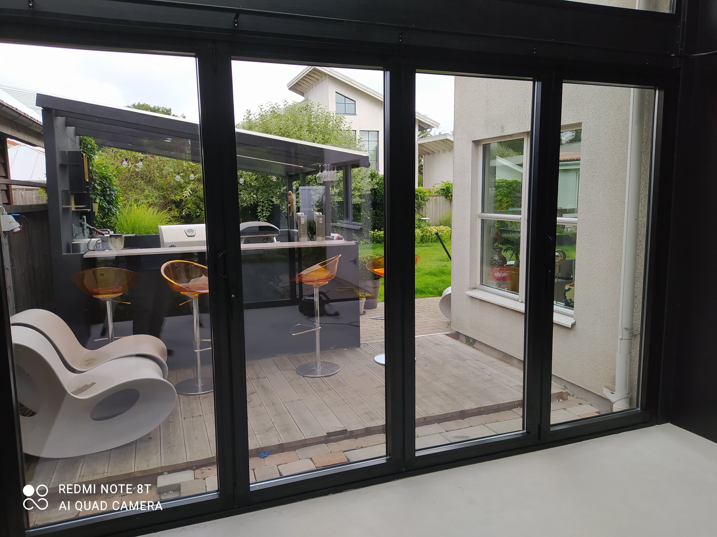 Ett uterum i glas med barstolar på altanen