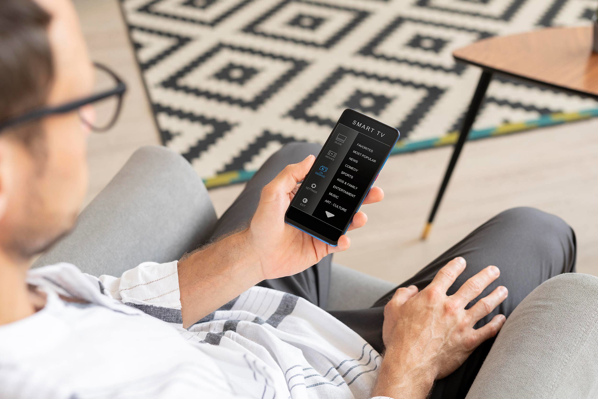 Man som styr sin smarta tv med mobiltelefonen