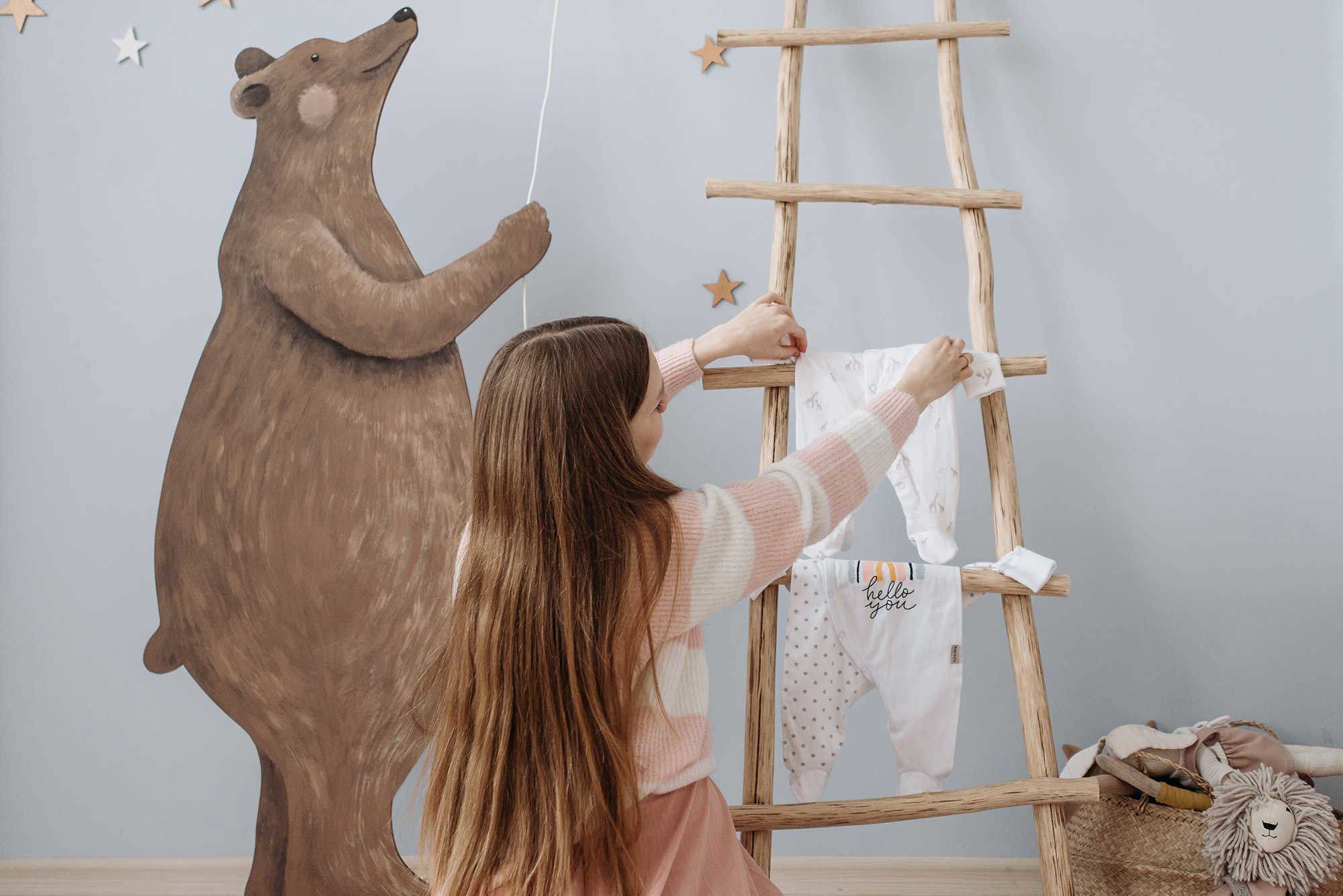 barn som hänger upp barnkläder på en stege i trä