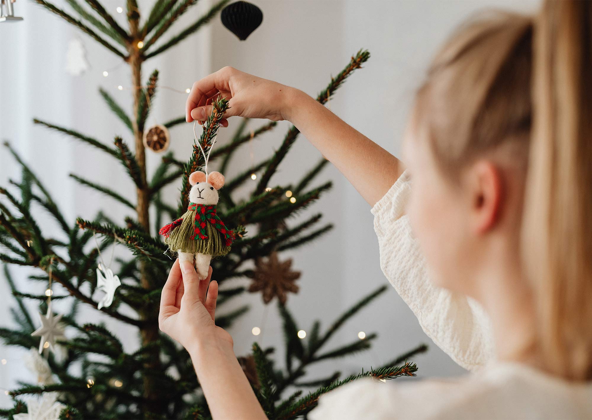 Tjej som pyntar en julgran