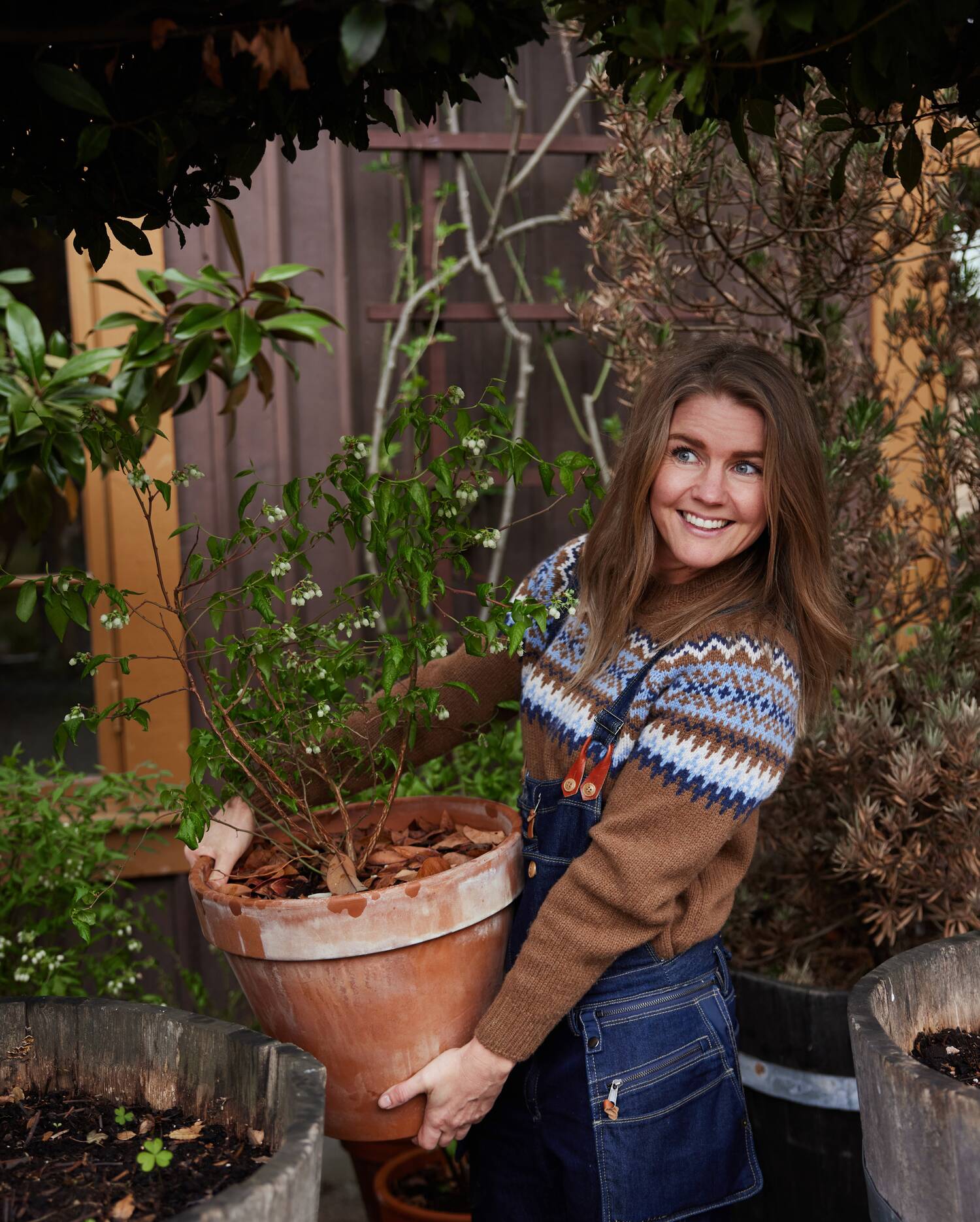 Tjej i trädgård som håller i en stor blomkruka