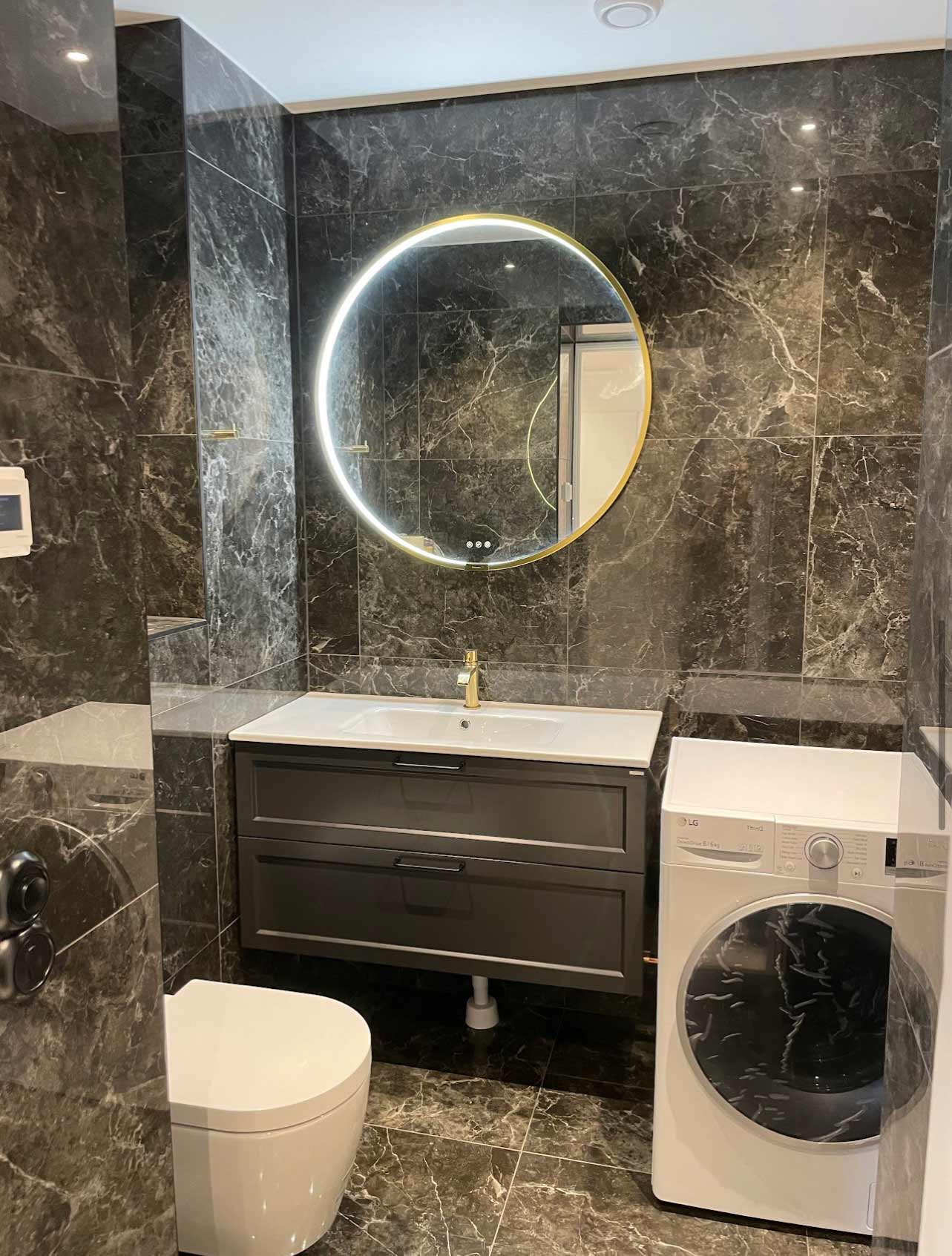 Renoverat badrum, svart kakel, marmor, gulddetaljer