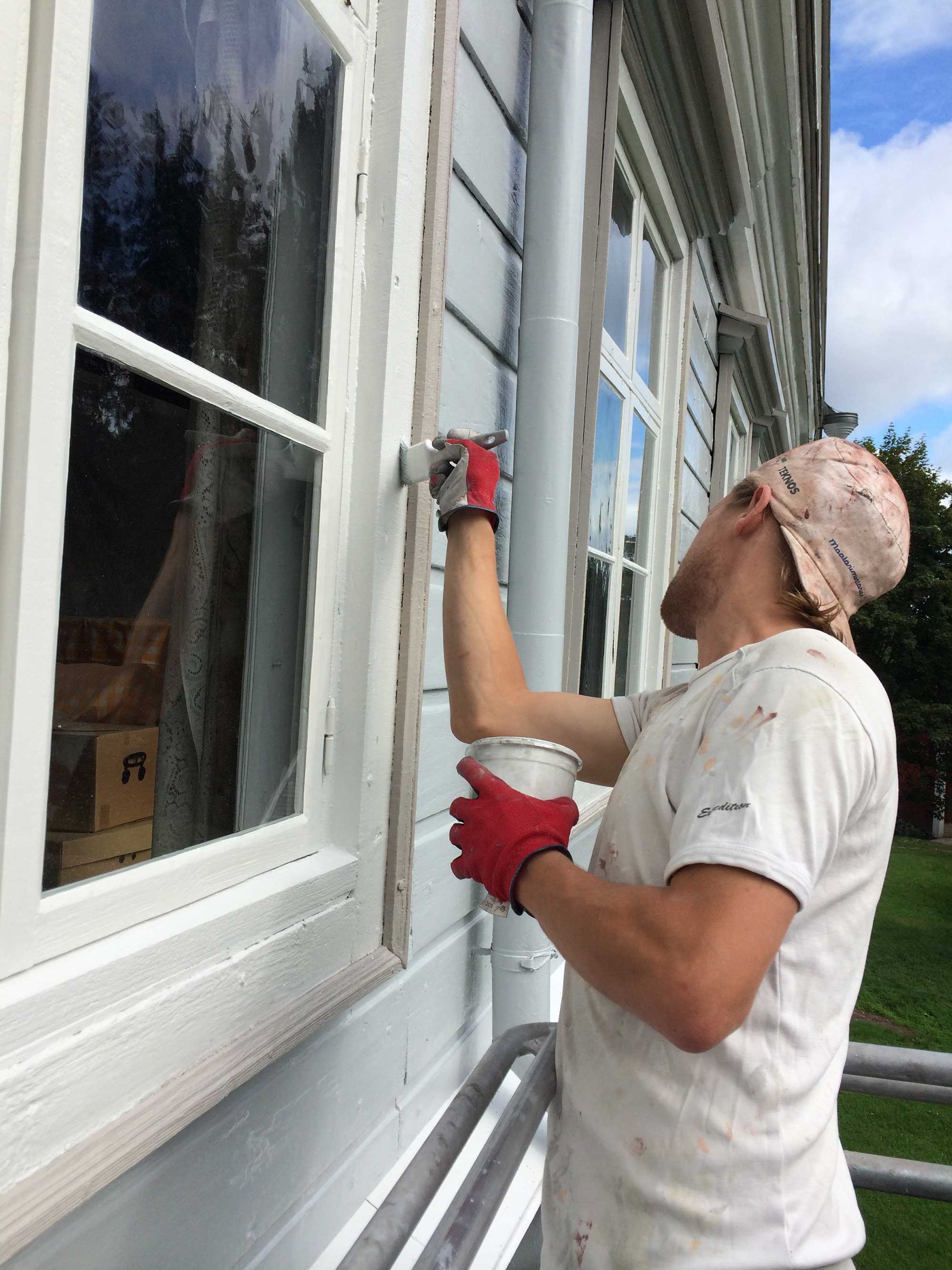 målare som målar husfasad i trä