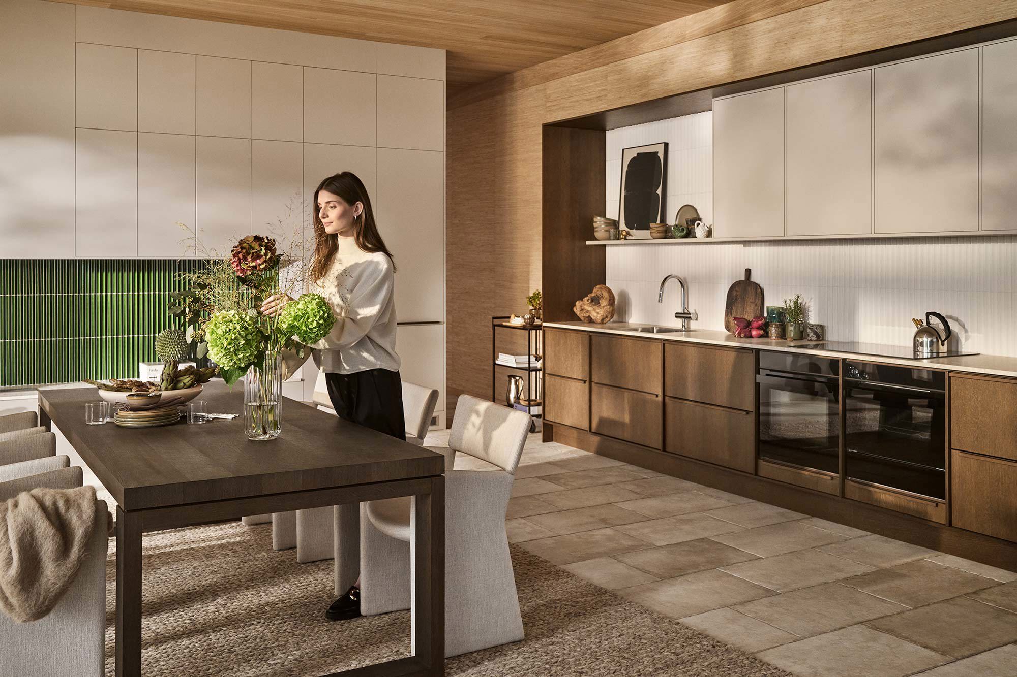 Kvinna som står och hanterar blommor i en vas i köket