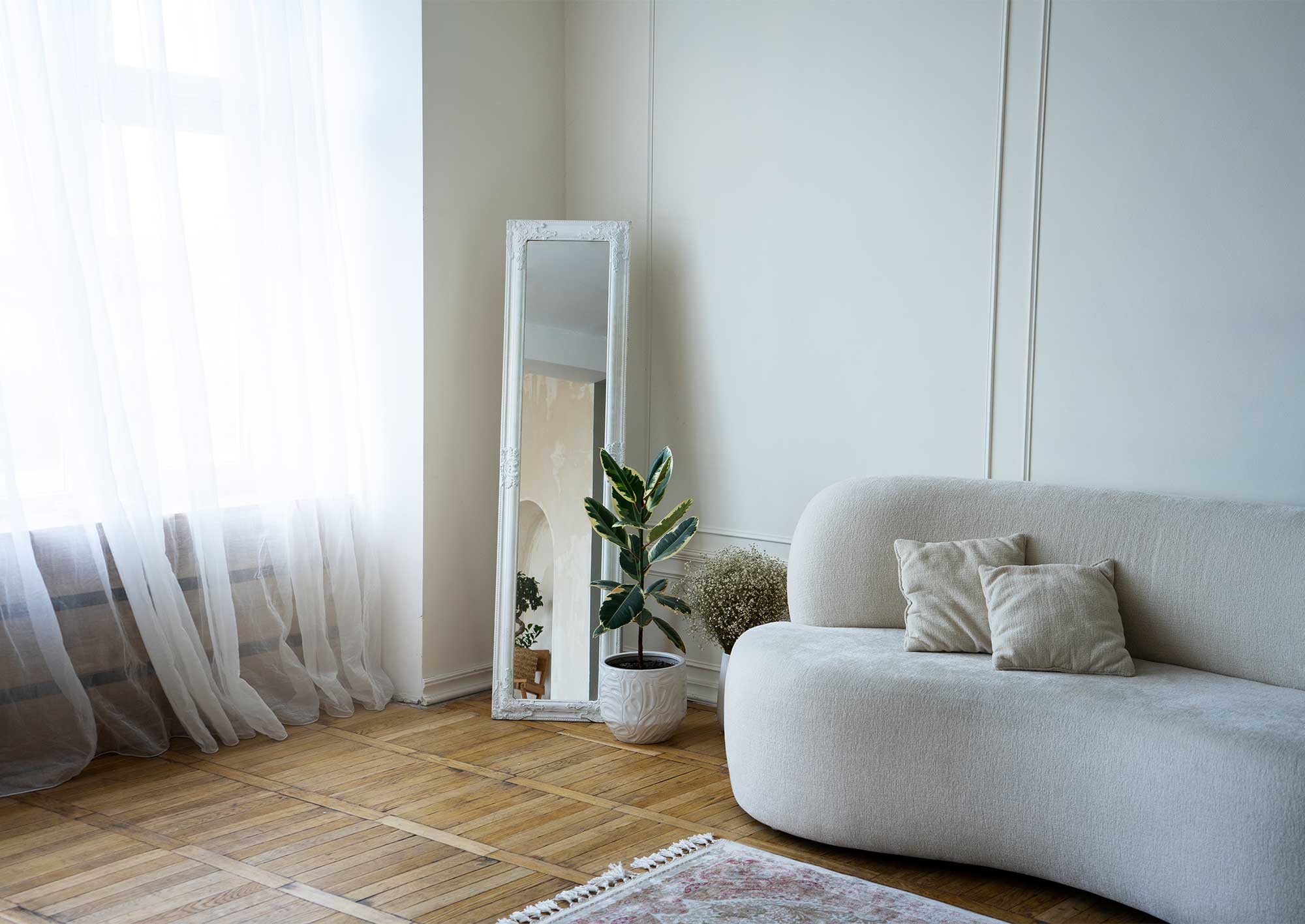 Litet vardagsrum i ljusa toner med en modern soffa och stora fönster