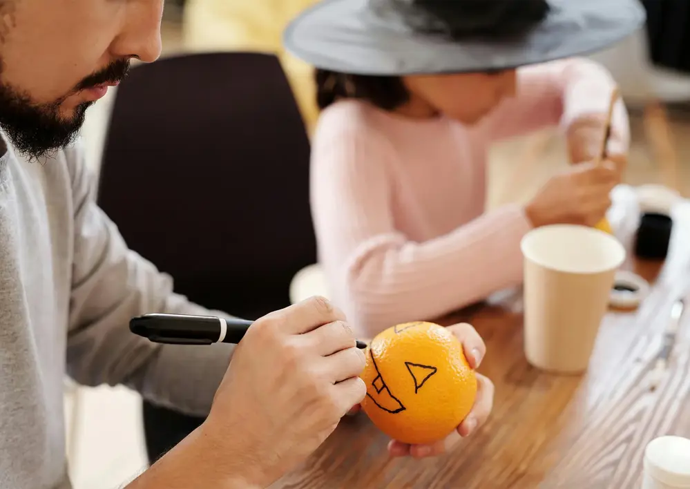 Man som målar en apelsin till halloween