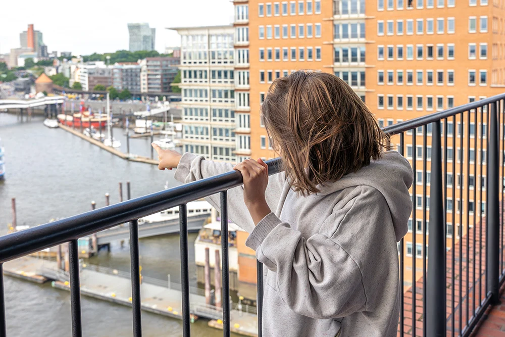 barn på balkong som pekar ut mot vatten