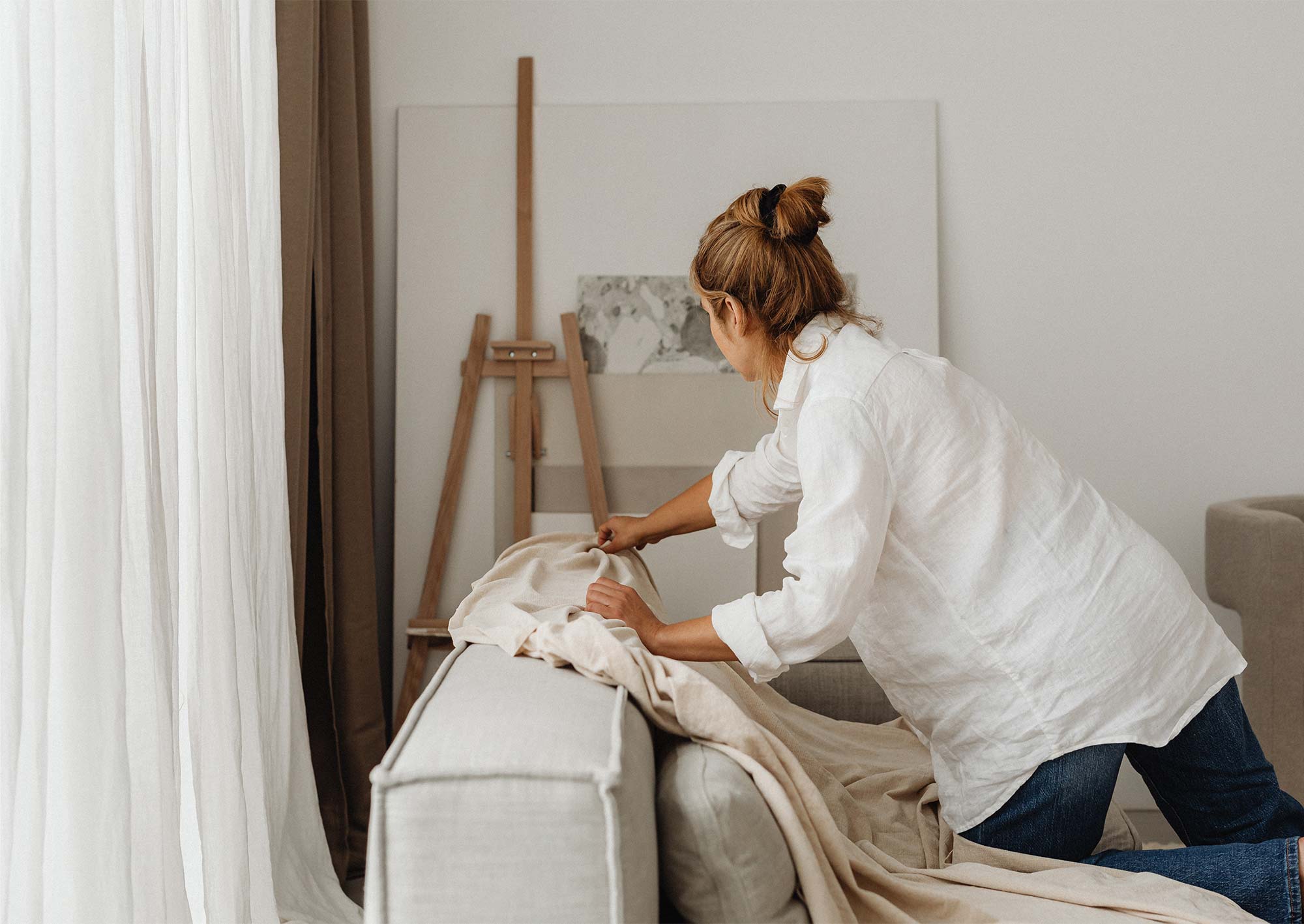 Kvinna som placerar en filt på en soffa