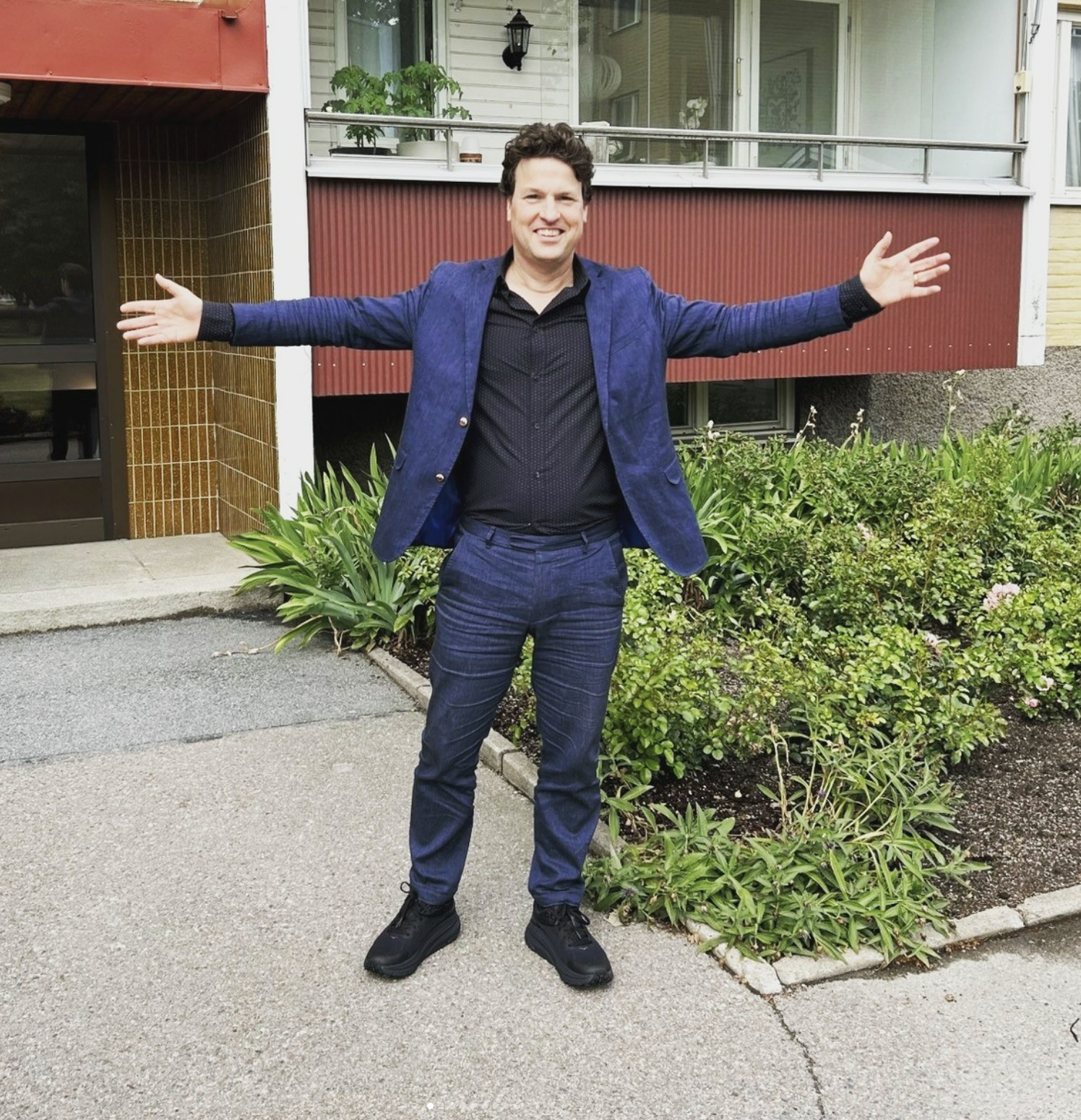 Mäklare välkomnar, person som står framför en port till ett flerfamiljshus