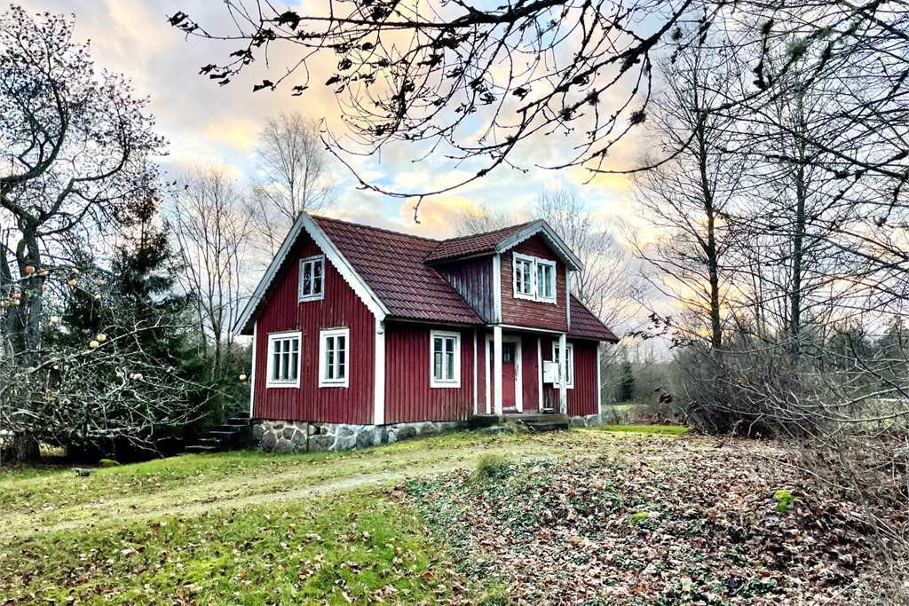 äldre rött fritidshus med vita knutar