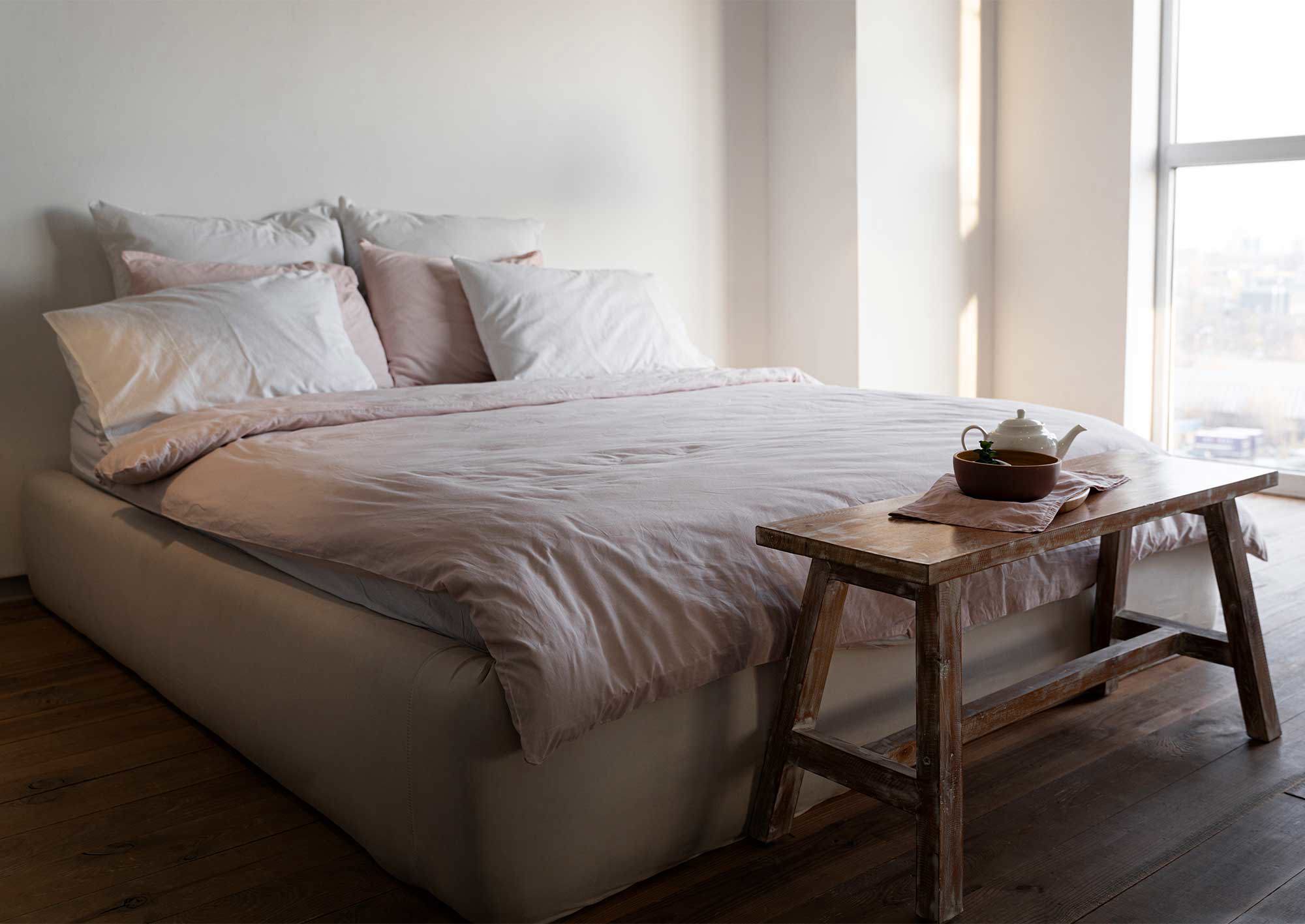 Säng placerad mot en vägg med ett bord framför med te på