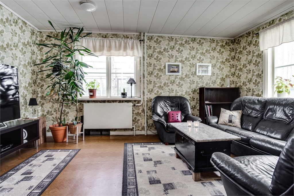 vardagsrum, tapeter med löv, skinnsoffor, stor växt