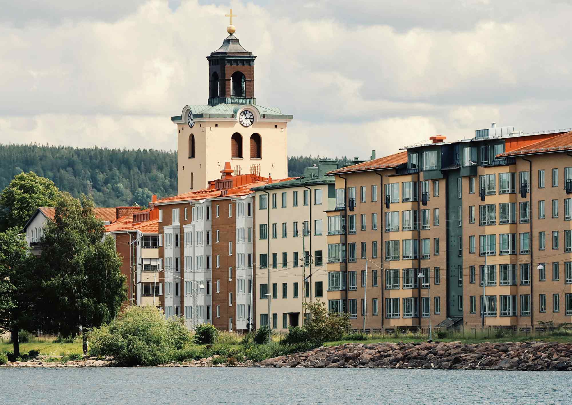 Flera lägenhetshus vid vattnet och en kyrka i bakgrunden