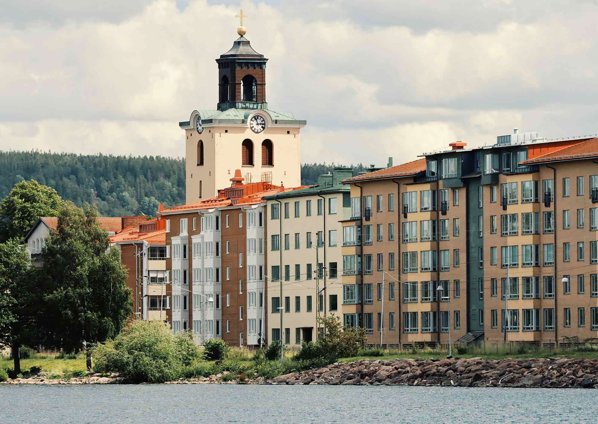 Flera lägenhetshus vid vattnet och en kyrka i bakgrunden