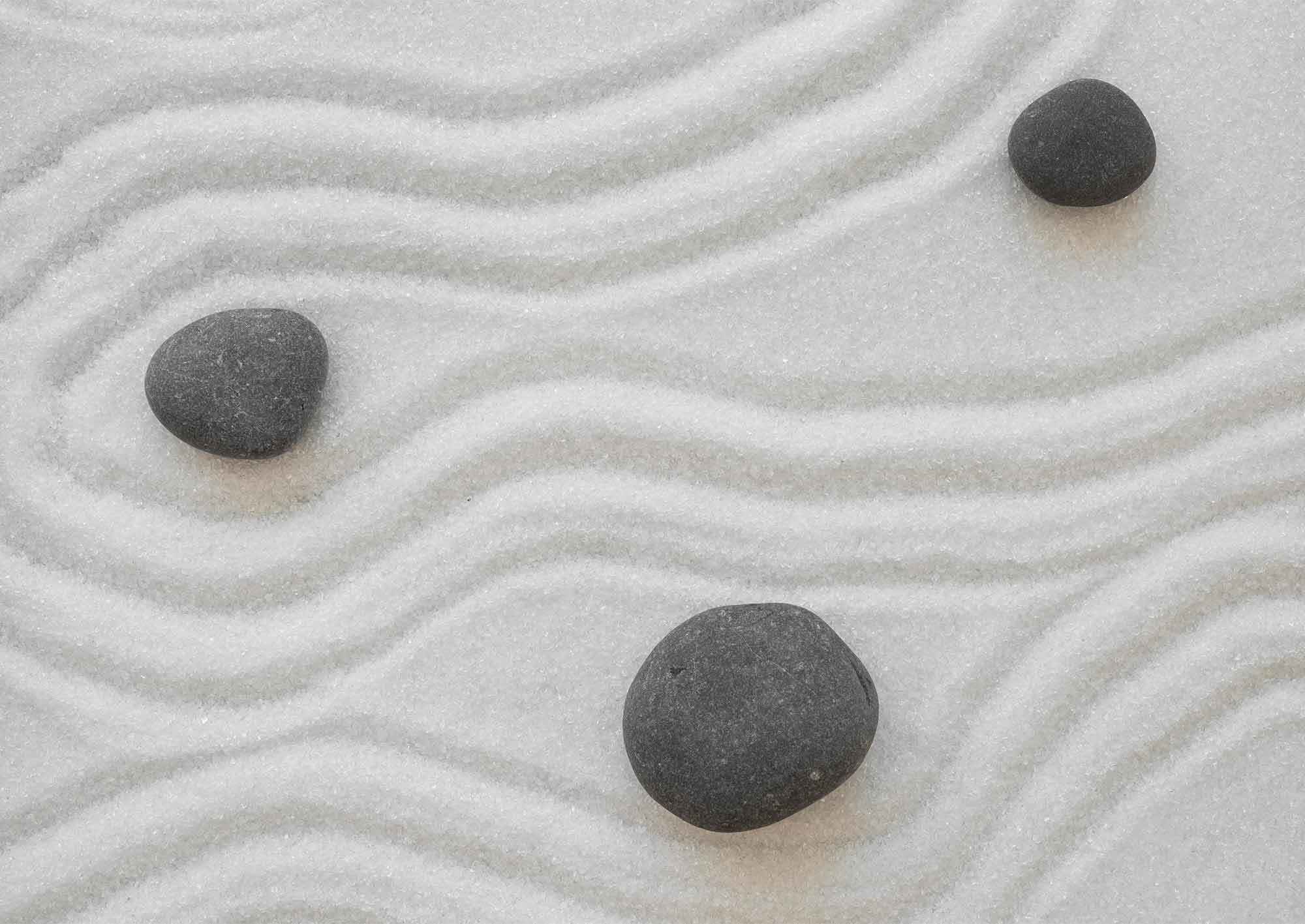 Tre svarta stenar i vit sand